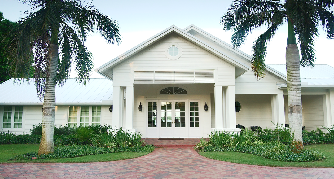 white painted home with palm trees in front